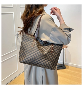 Detail of vintage tote bag with letter print pattern and gold bow metal buckle