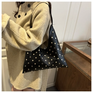 Detail of black PU leather tote bag featuring gold metal rivets and triangular structure