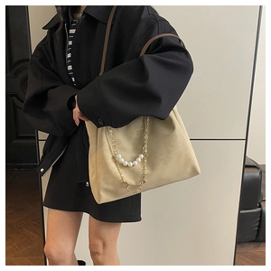 Detail of large tote bag with elegant gold chain and white pearl strand decoration