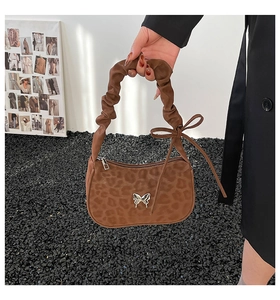 Macro detail of brown leopard print bag with silver butterfly buckle and pleated strap