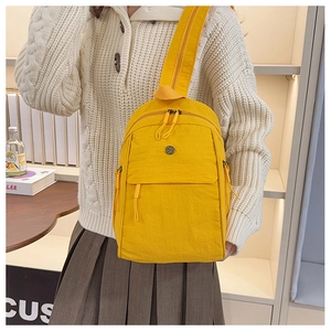Detailed view of bright yellow water-resistant nylon backpack with multiple zipper pockets