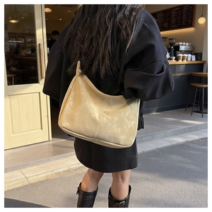 Close-up of a vintage cream hobo bag with matte texture in an outdoor cafe setting