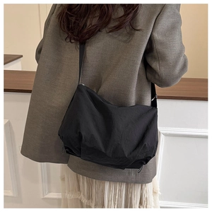 Side view of black nylon tote bag on shoulder showing its natural drape and sleek texture