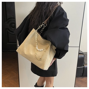 Detail of khaki tote bag with gold chain strap, white pearls, and clover charm