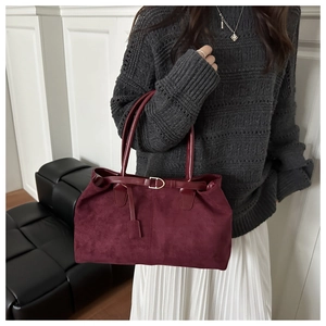 Close-up of suede tote bag texture with gold buckle and elegant burgundy finish