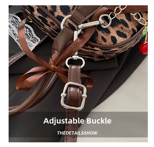Detail of adjustable leather strap and silver metal buckle on leopard print shell bag