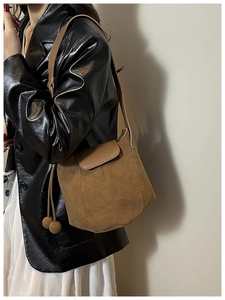 Détail du sac seau en daim marron avec cordon de serrage et bandoulière en cuir