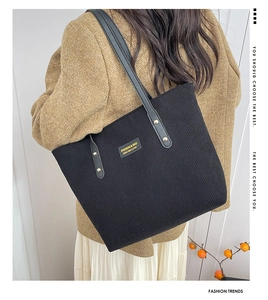 Detail of black corduroy tote bag with leather handles and gold rivet accents