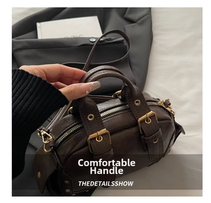 Detail of vintage brown leather handbag featuring golden buckles and rivets texture