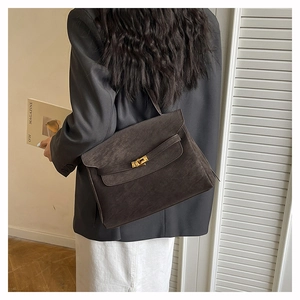 Charcoal suede crossbody tote bag shown on model with gold hardware and flap closure