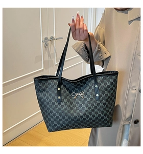 Detailed close-up of tote bag featuring gray M-pattern print and silver bow buckle