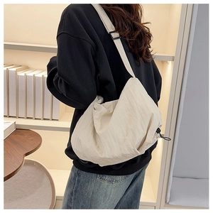 Detail of off-white nylon tote bag with adjustable strap and drawstring toggle closure