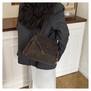 Detail of dark brown suede shoulder bag with elegant gold metal buckle and leather strap