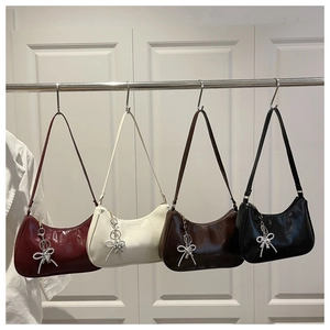 Glossy hobo bags in four colors with pearl bow charms hanging on a white wooden door