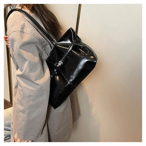 Macro shot of glossy black leather tote bag with elegant silver metallic buckle detail