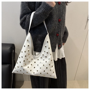 Close-up of a white leather underarm bag featuring metallic silver studs and a chic strap