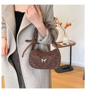 Close-up of leopard print shoulder bag with silver butterfly and scrunchie strap