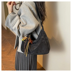 Detail of a large black suede crescent bag featuring star and animal charms on the side