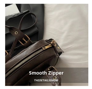 Detail of vintage dark brown faux leather bag with smooth metal zipper and adjustable strap