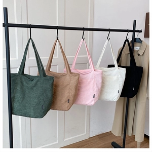 Gros plan détaillé de sacs cabas en velours côtelé de cinq couleurs sur un cintre épuré