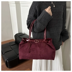 Close-up of burgundy suede tote bag featuring a gold D-ring buckle and slim leather handles