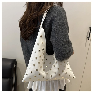 Detail van witte driehoekige leren tas met gouden studs over de schouder gedragen