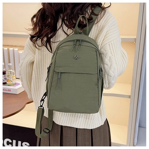 Detail of multi-pocket dark green nylon backpack with woven straps and top handle