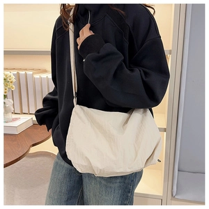 Detail of off-white nylon tote bag with adjustable strap in a minimalist home setting