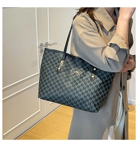 Detail of M-pattern large tote bag featuring golden bow clasp and black leather straps