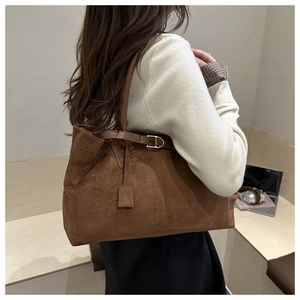 Detail shot of a brown suede tote bag with metal buckle and shoulder strap in a cafe