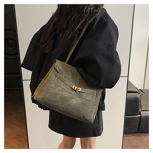 Detail of dark olive suede messenger bag with metal turn-lock and leather strap
