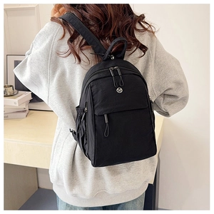 Close-up of black nylon multi-pocket mini backpack with silver metal zippers and logo