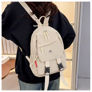 Rear view of model wearing a beige nylon waterproof backpack in a warm indoor setting