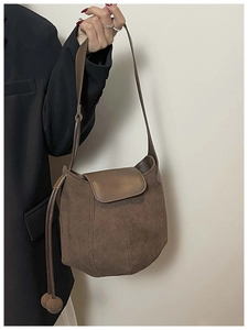 Détail du sac seau en daim marron foncé avec pendentif sphérique latéral et rabat
