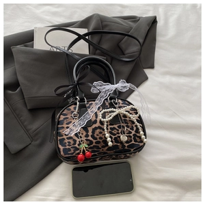 Flat lay of leopard print satchel bag featuring cherry and lace bow charms