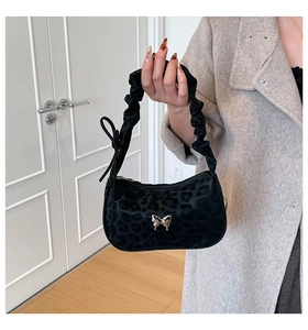 Detail of silver butterfly buckle and leopard pattern on black PU shoulder bag