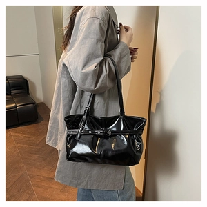 Detailed close-up of glossy black patent leather tote bag with stylish buckle strap