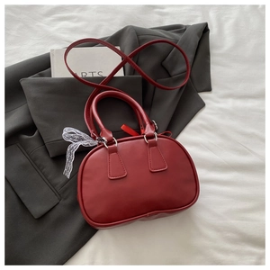 Detail of red leather doctor bag with white lace bow on a dark grey blazer