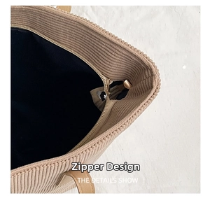 Detail view of khaki corduroy tote bag featuring a secure top zipper and leather strap