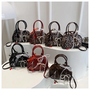 Close-up of stylish Boston bags with leopard print, pearl bows and cherry charms