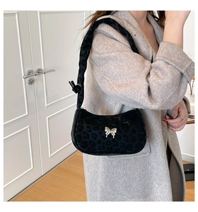 Close-up of leopard print shoulder bag with a gold metal bow on a grey wool coat