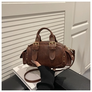 Close-up of vintage brown leather Boston bag featuring gold hardware and metal rivets
