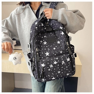 Close-up of black star pattern backpack with multiple zipper pockets and plush star charm