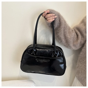 Dettaglio borsa Boston nera lucida con fiocco decorativo e scritta del brand