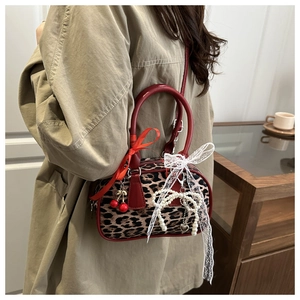 Close-up of leopard print pillow bag with red bow, cherry pendant and lace details