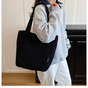 Détail d'un sac cabas en velours côtelé noir avec étiquette mode et bandoulière large