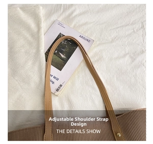 Detail view of the adjustable beige leather strap on a brown corduroy tote bag