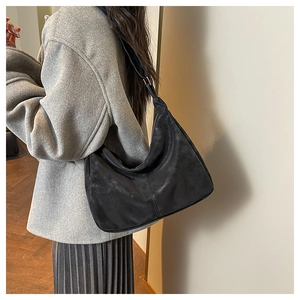 Close-up of black suede hobo bag showing adjustable wide shoulder strap and silver buckle