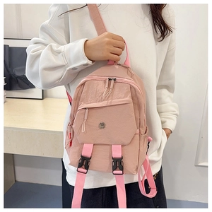 Pink nylon mini backpack with double buckle straps worn by model for daily commute