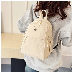 Detail of a beige mini nylon backpack worn as a crossbody bag for a casual look